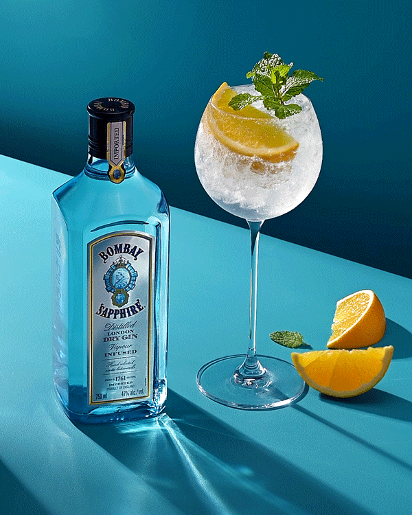 Bombay Sapphire gin bottle video with iced cocktail, garnished with orange wedges and mint leaves