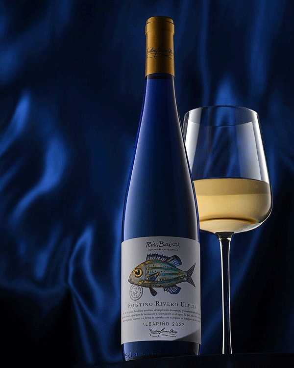 Cinemagraph video of white wine bottle and glass on a blue curtain background